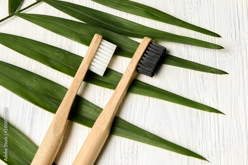 bamboo toothbrushes on white wood background with tropical leaf. Place for text. Ecoproduct.   eco-friendly photo