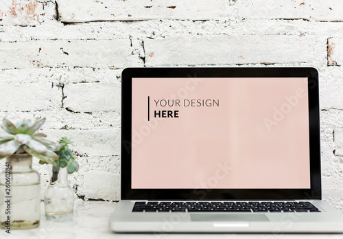Laptop in Front of White Brick Wall Next to Plants Mockup
