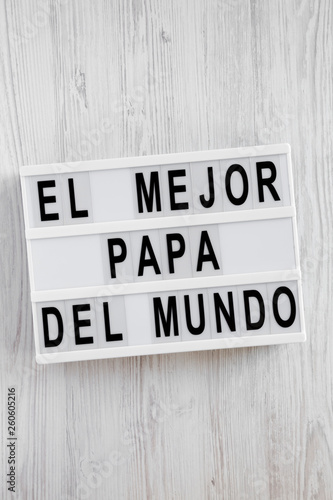 'El Mejor Papa Del Mundo' words on lightbox over white wooden surface, overhead view. Top view, from above, flat lay. Father's day.