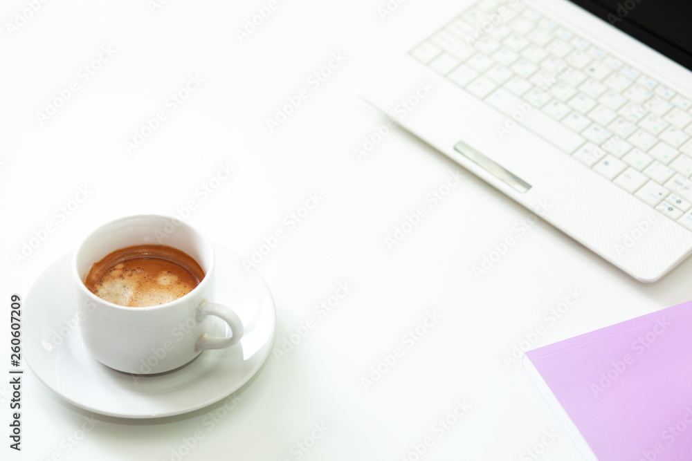 Coffee cup, laptop and lavender notpad on white table. Selective focus. Coffee cup, laptop and lavender notpad on white table. Selective focus.