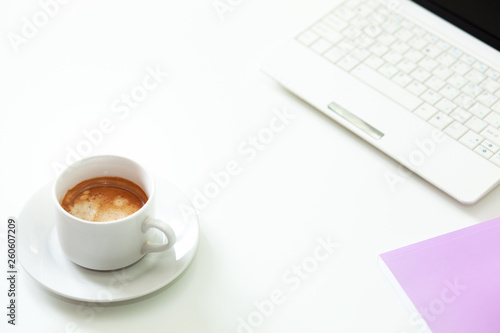 Coffee cup, laptop and lavender notpad on white table. Selective focus.