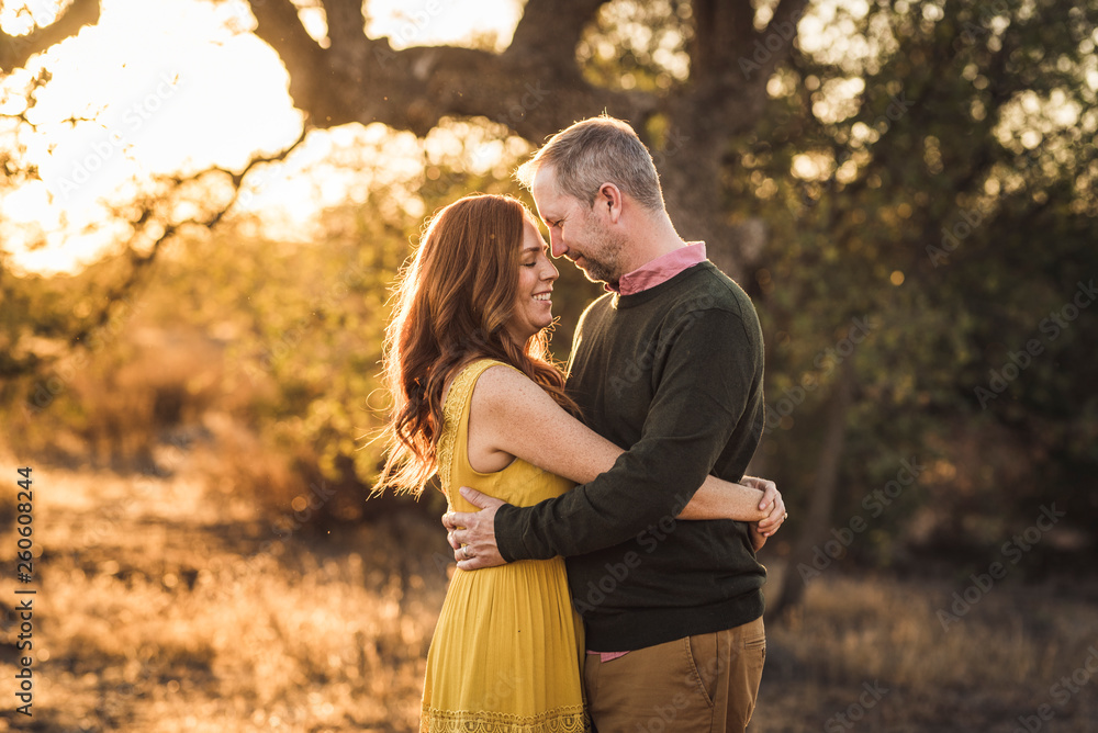Woman embracing husband while in California field during sunset Woman embracing husband while in California field during sunset