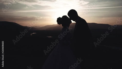 a lovely wedding couple kisses and nurtures at sunset