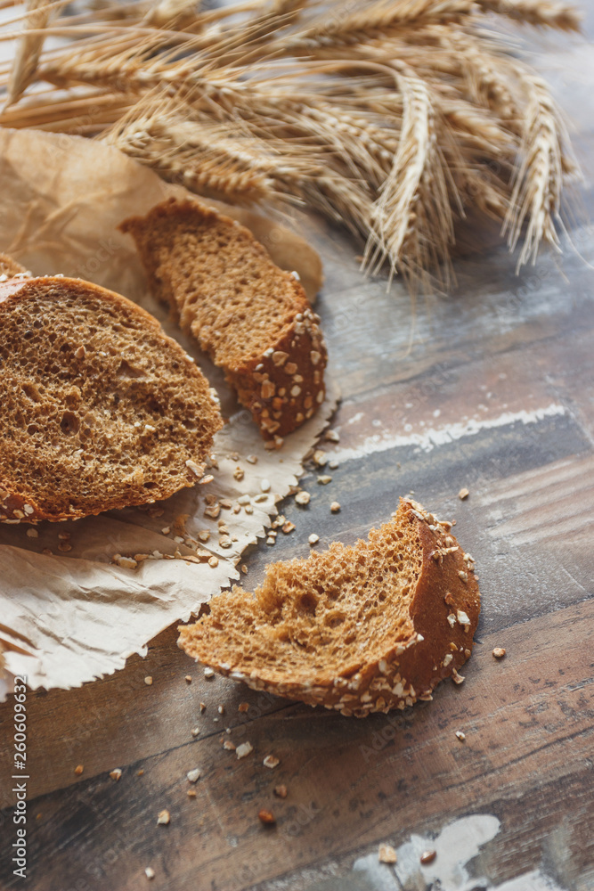 Handmade bread with bran and ears of wheat, wooden background Handmade bread with bran and ears of wheat, wooden background