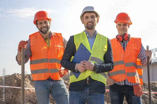 male workers engineers in helmets look into the camera and smile, at a construction site