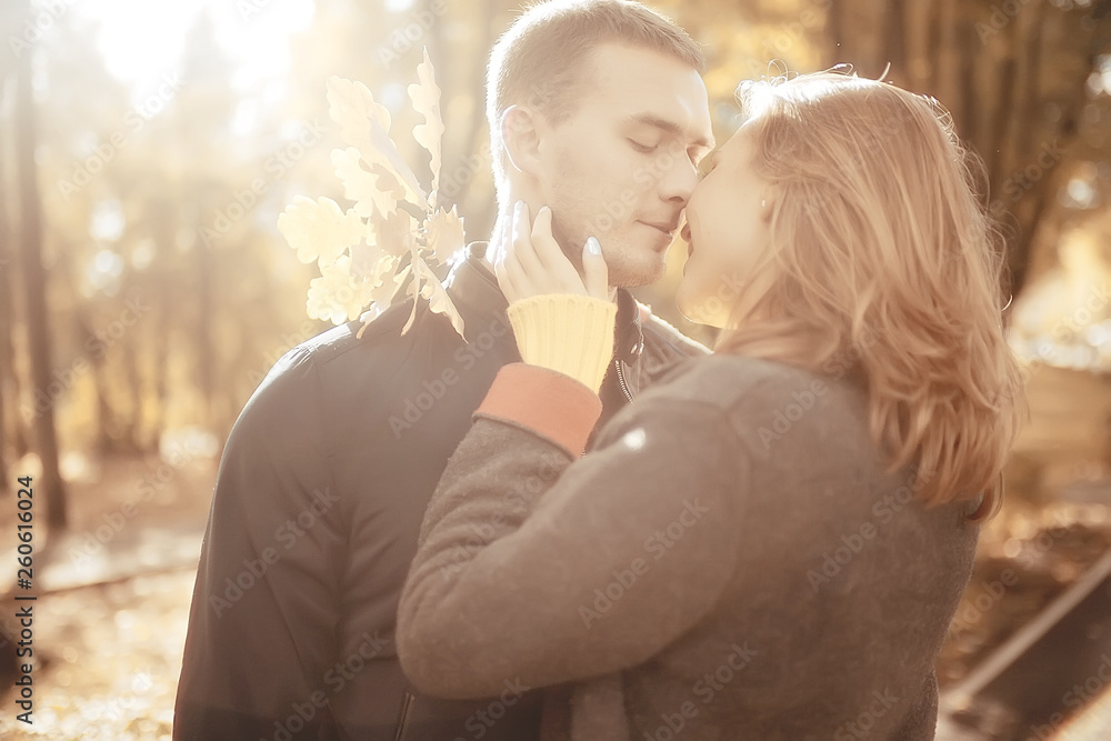 Fototapeta premium sun rays in the autumn park, a couple in love / young man and woman are walking, autumn view of the sunny park, the rays of the sun, warm autumn background