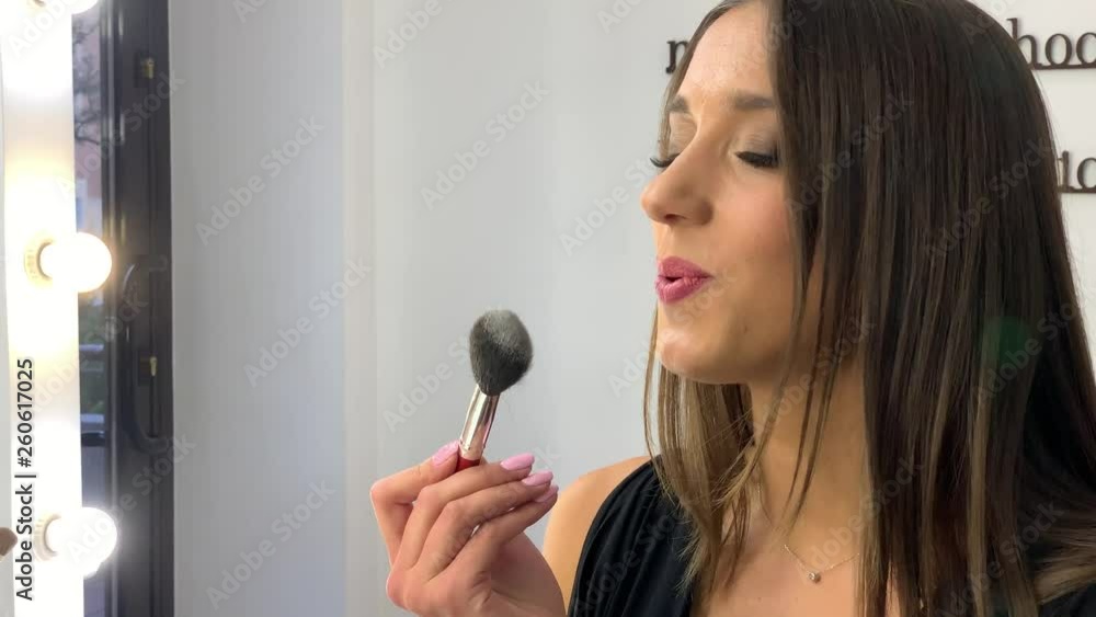 Woman applying make up and looking through the mirror in the morning time Woman applying make up and looking through the mirror in the morning time