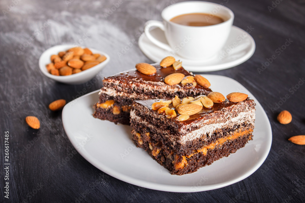 Chocolate cake with caramel, peanuts and almonds on a black wooden background. Chocolate cake with caramel, peanuts and almonds on a black wooden background.