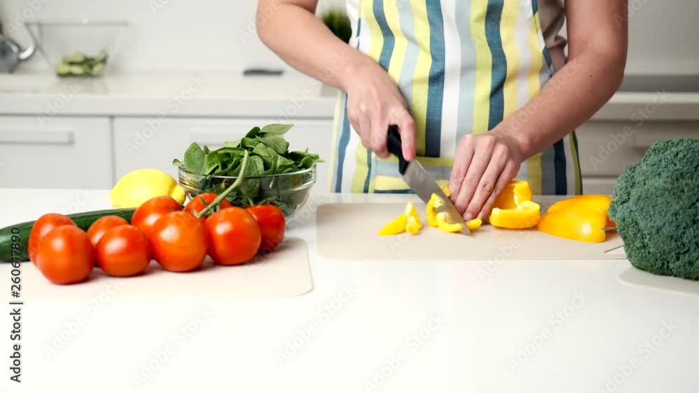 woman prepares a salad in the kitchen, at the end a beagle dog appears, and examines vegetables