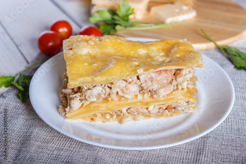 Lasagna with minced meat and cheese on white wooden background.