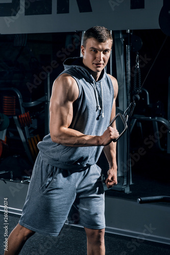 Handsome muscular sportman working out, training arms in gym, pumping up muscles bicep and tricep with exercise machine. Sport, man physics, fitness and bodybuilding concept