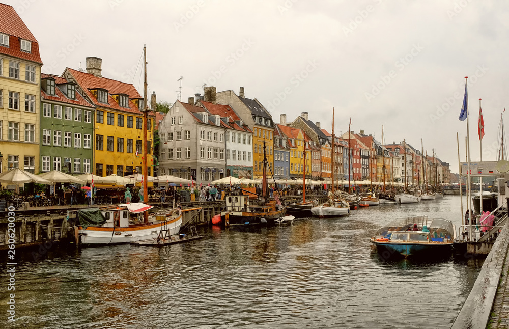Panorama of north side of Nyhavn with colorful facades of old houses and old ships in the Old Town of Copenhagen, capital of Denmark.