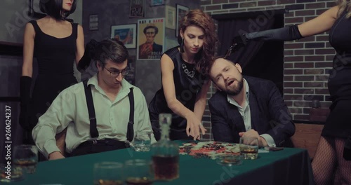 Beautiful women rob men. Girl takes all the chips and money, others threaten the men with a pistol.