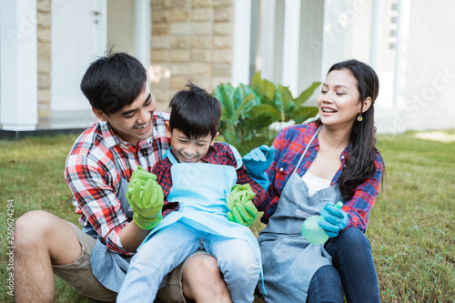 famiy and kid sitting on a grass in their house garden after gardening together smiling and having fun photo