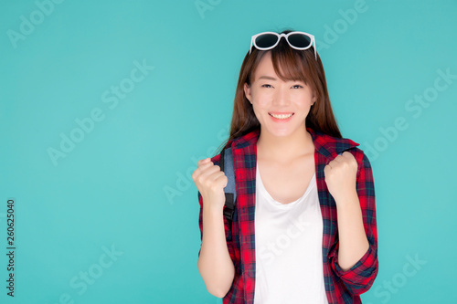 Beautiful portrait young asian woman wear sunglasses on head smile confident and excited summer holiday isolated blue background, model girl fashion having backpack, travel concept. © N_studio