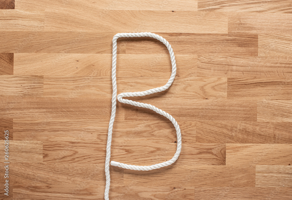 The letter B formed with white rope on a wooden table The letter B formed with white rope on a wooden table