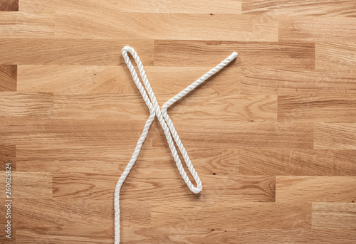 The letter X formed with white rope on a wooden table