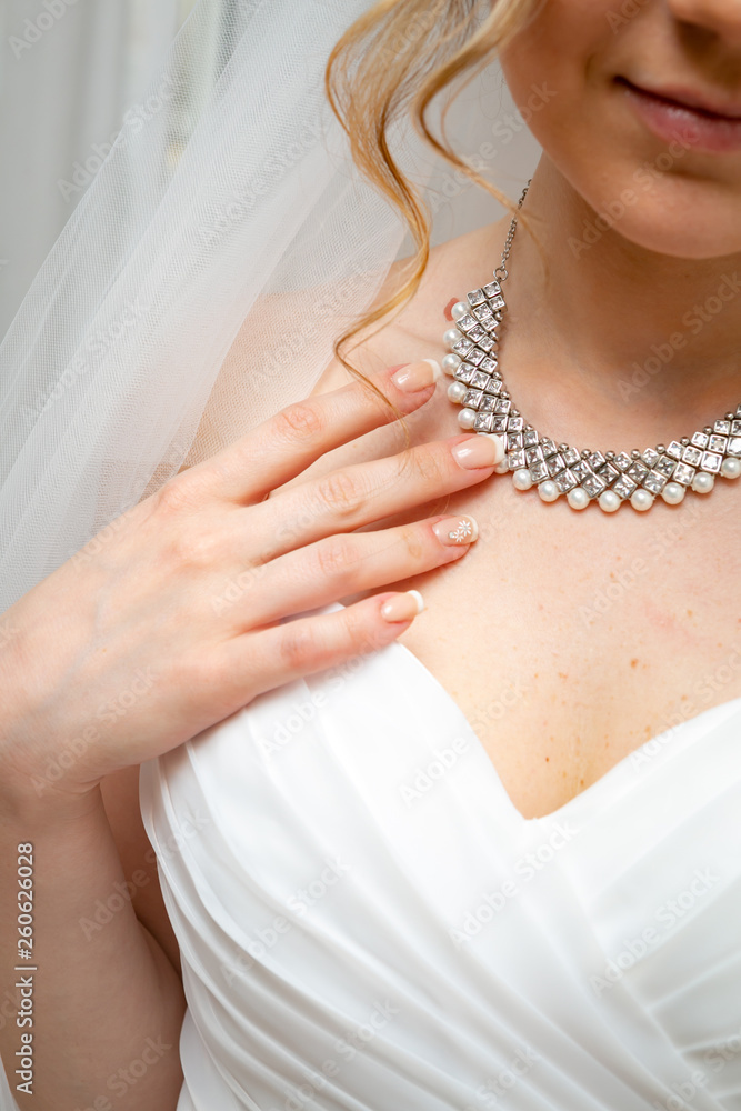 The bride in a white wedding dress with a veil and a silver necklace.