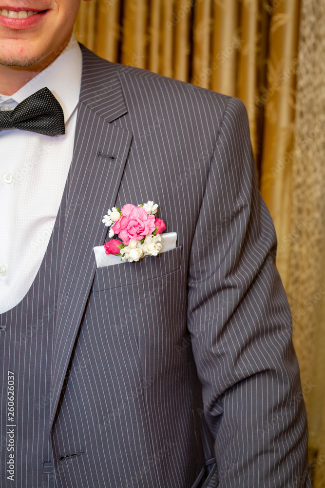 The groom in a gray pinstripe suit, white shirt with black bow tie, with  flowers in his jacket pocket. Stock Photo | Adobe Stock