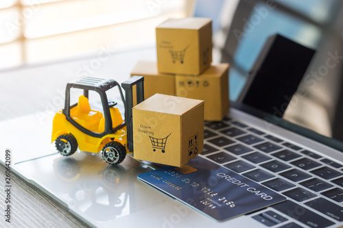 Mini forklift truck load cardboard box with text online shopping and mock up of credit card on laptop keyboard. Logistics and transportation management ideas and Industry business commercial concept.