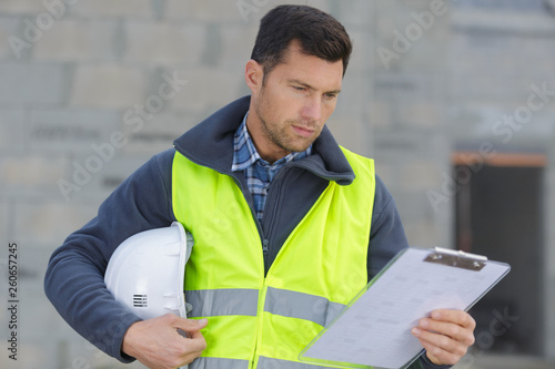 builder in hardhat with clipboard outdoors