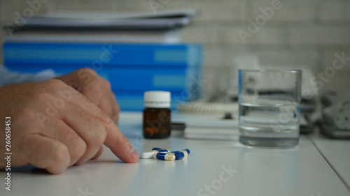 Businessman Select and Take Pills for a Medical Treatment from the Table