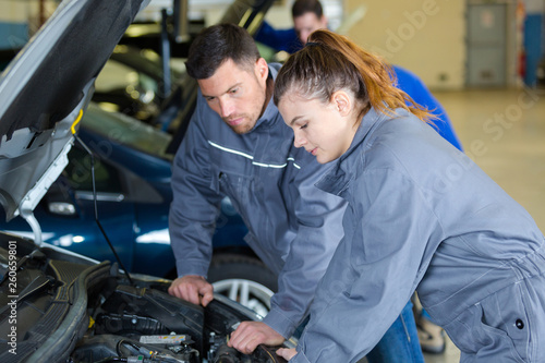 mechanic and apprentice looking at cars engine