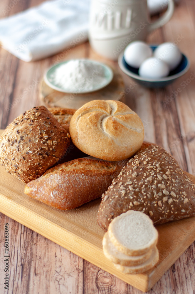 Various baked breads and rolls on wooden table