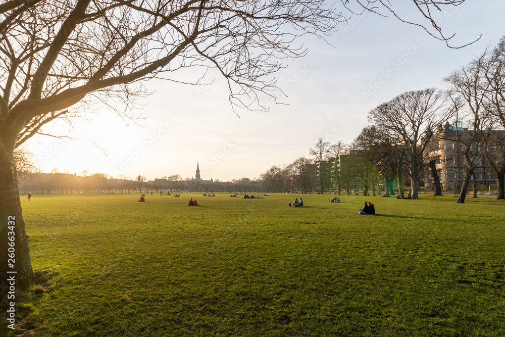 EDINBURGH, SCOTLAND, 20 February 2019, People watching sunset sitting on the green grass near university