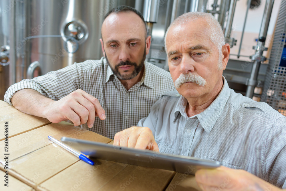 winemakers in cellar using electronic tablet to control wine quality winemakers in cellar using electronic tablet to control wine quality