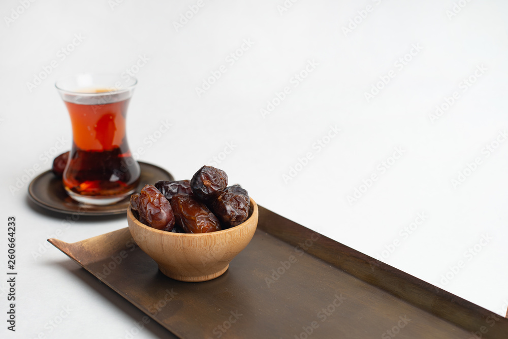Ramadan Kareem Festival, Dates at wooden bowl with cup of black tea on white isolated background Ramadan Kareem Festival, Dates at wooden bowl with cup of black tea on white isolated background