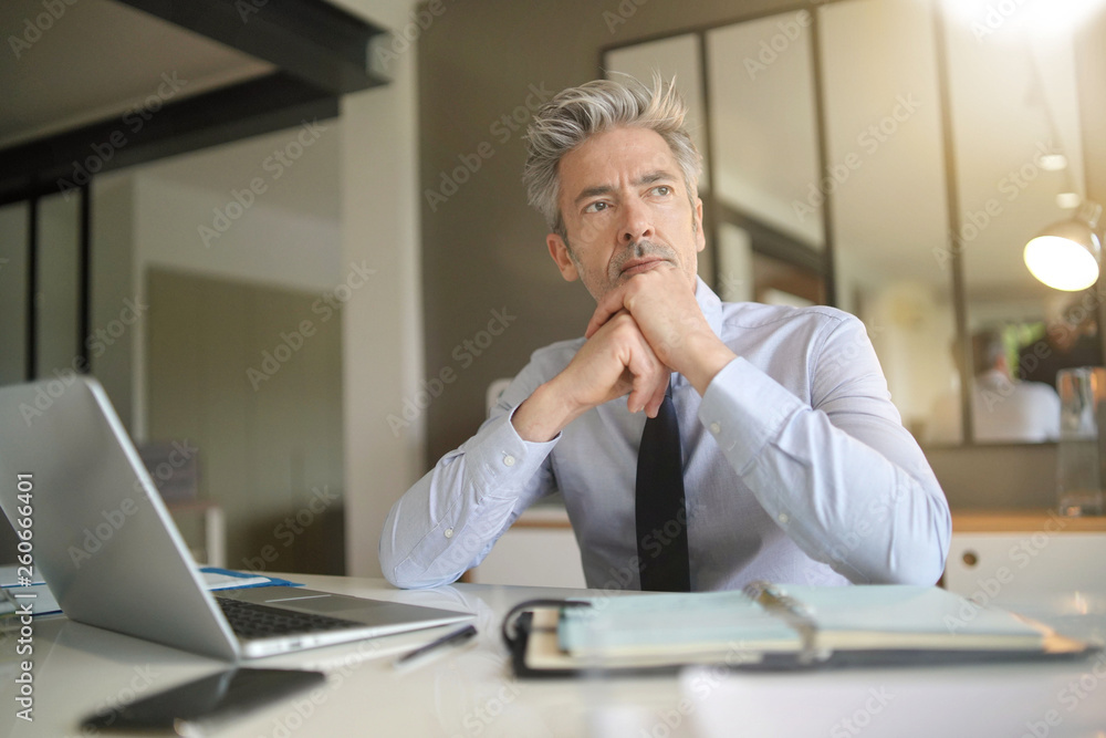 Handsome businessman in office contemplating Handsome businessman in office contemplating