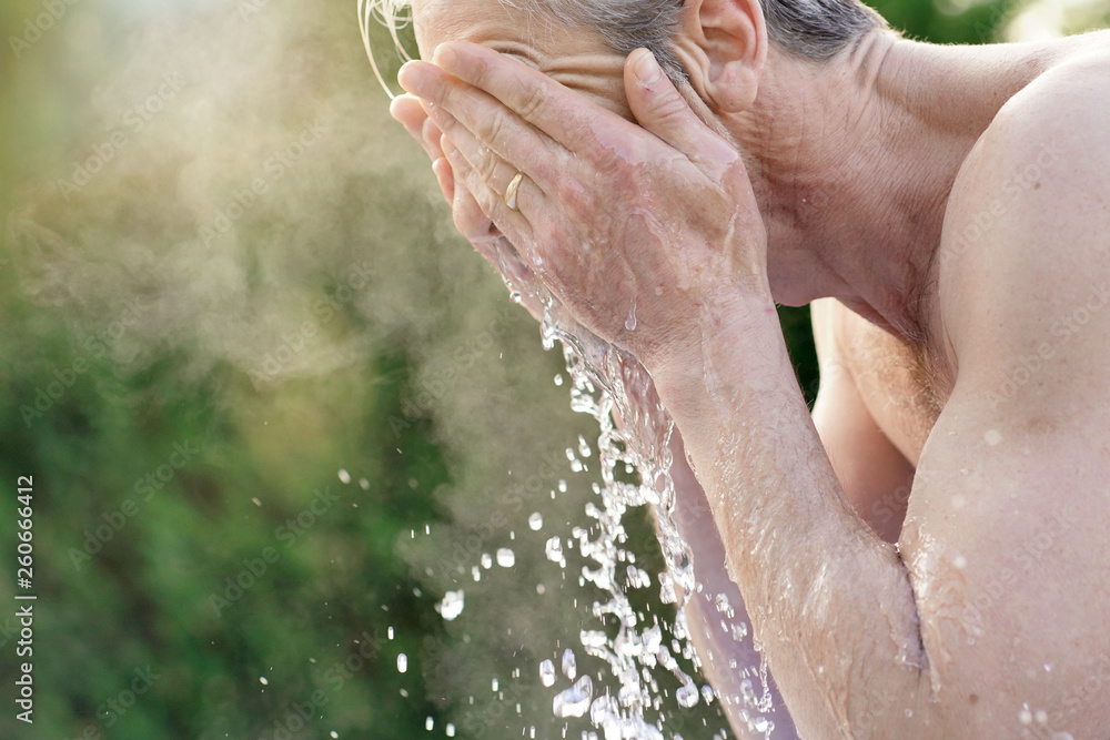Fototapeta premium Portrait of topless man splashing face with water