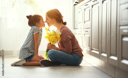 happy mother's day! child daughter gives mother a bouquet of flowers to narcissus and gift.
