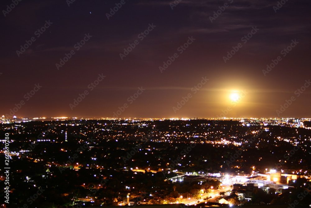 A view of the city at night with misty moon in the sky