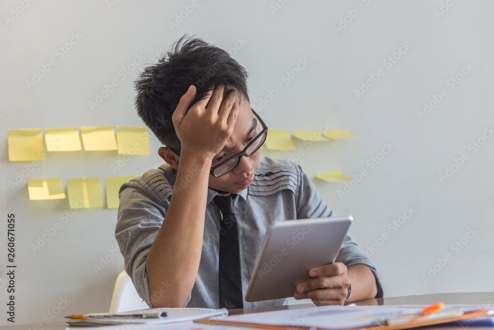 Asian businessman looking at bad financial results on the tablet Asian businessman looking at bad financial results on the tablet