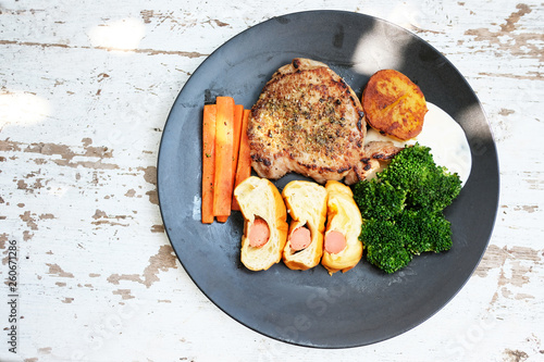 Meat steak with grilled vegetables and spices placed in a plate on a wooden table