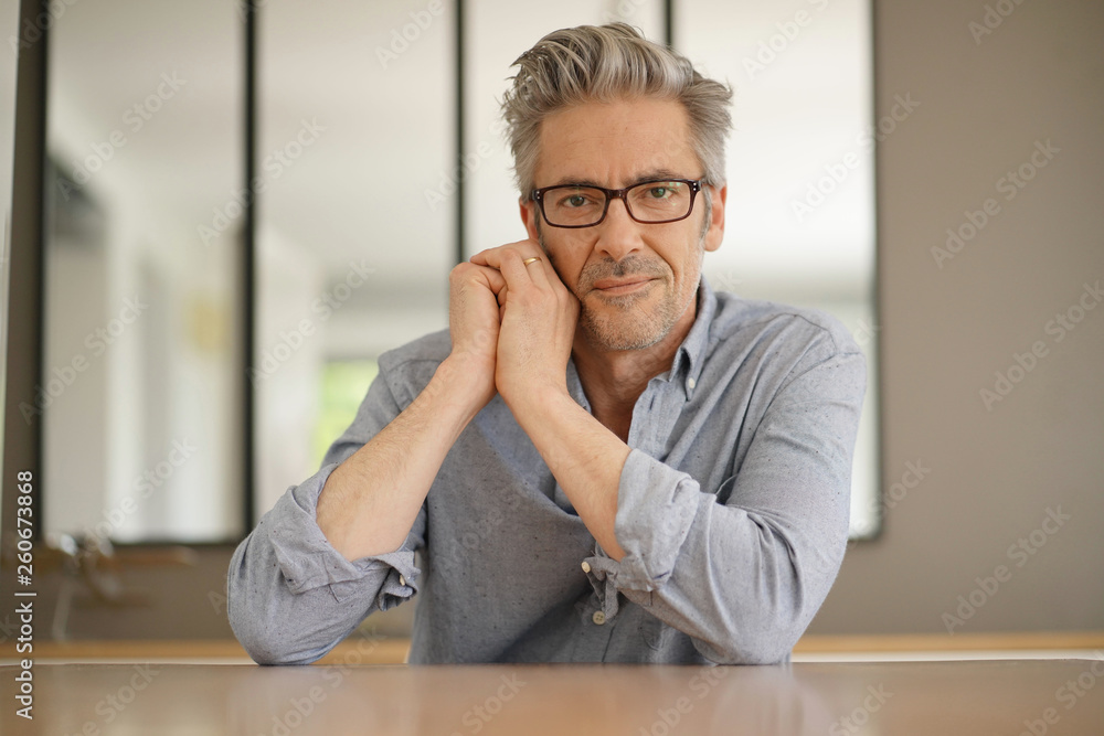 Fototapeta premium Portrait of handsome mature man wearing glasses smiling at camera
