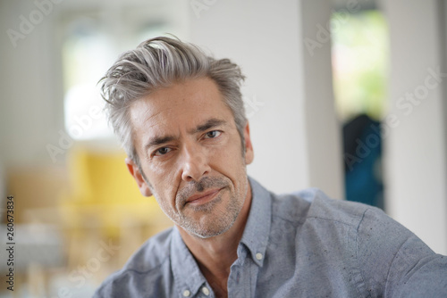 Portrait of handsome mature man looking at camera in contemporary home