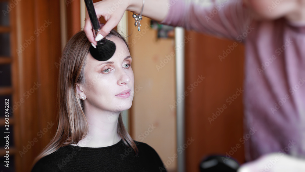 Process of making makeup. Make-up artist working with brush on model face. Portrait of young woman in home interior. Process of making makeup. Make-up artist working with brush on model face. Portrait of young woman in home interior.