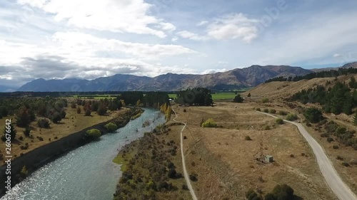 Wide drone shot following cyclists besides beautiful Cluth River, New Zealand in autumn. photo