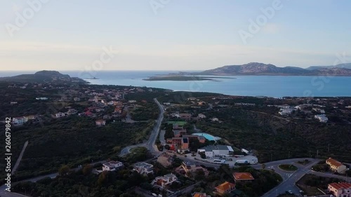 Aerial of a pretty village in Sardinia, Italy. Sunrise on the coast, mountains in the background photo