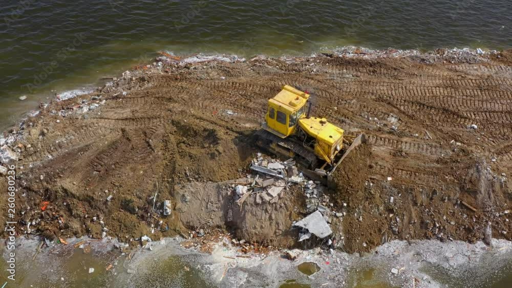 Yellow bulldozer works on river bank Yellow bulldozer works on river bank