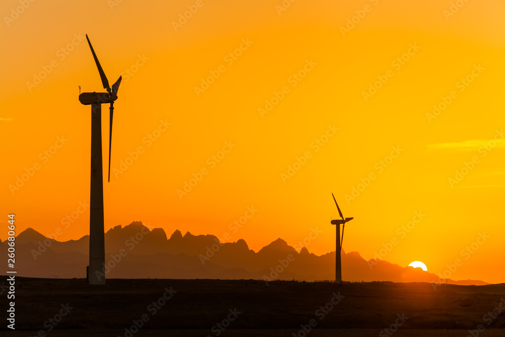 Obraz premium Big wind turbines in the desert against mountains