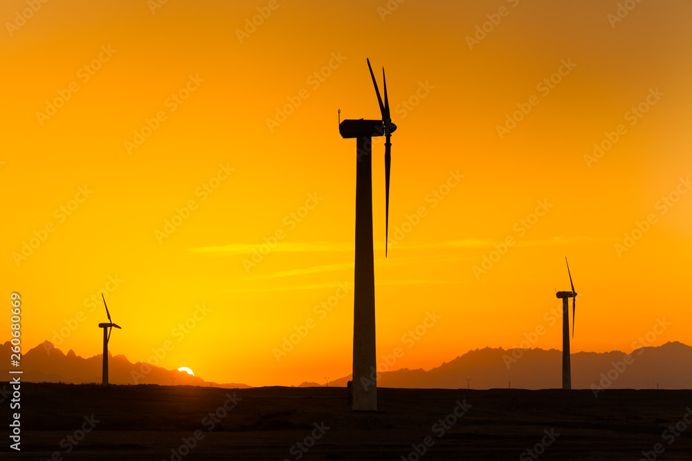 Obraz premium Big wind turbines in the desert against mountains