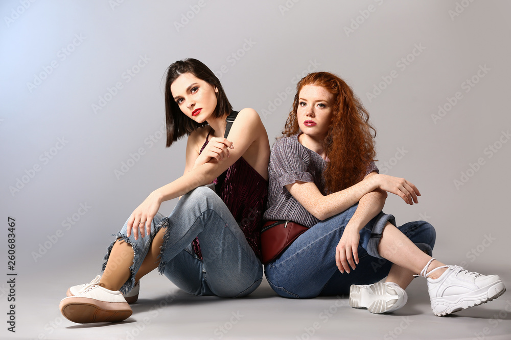 Portrait of fashionable young women on grey background