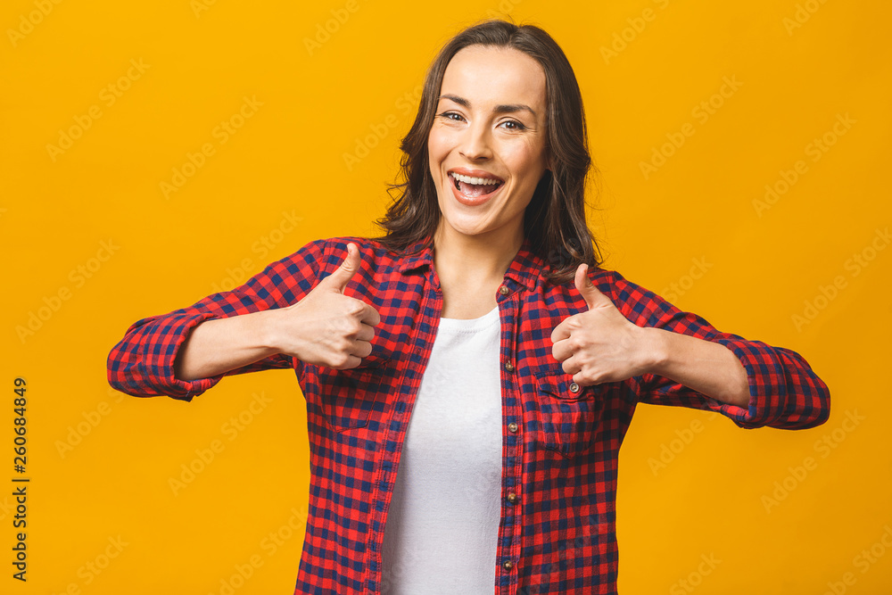 Portrait of a pretty happy woman in casual posing isolated on a yellow background. Thumbs up. Portrait of a pretty happy woman in casual posing isolated on a yellow background. Thumbs up.
