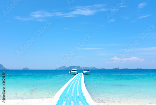 Plastic floating walkway bridge and pier on blue sea water in tropical island under bright blue sky in sunny day 