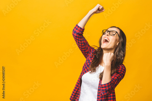Winning success woman happy ecstatic celebrating being a winner. Dynamic energetic image of multiracial Caucasian Asian female model isolated on yellow background waist up. photo