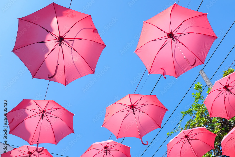 Bright red umbrellas hanging in the air with clear blue sky background